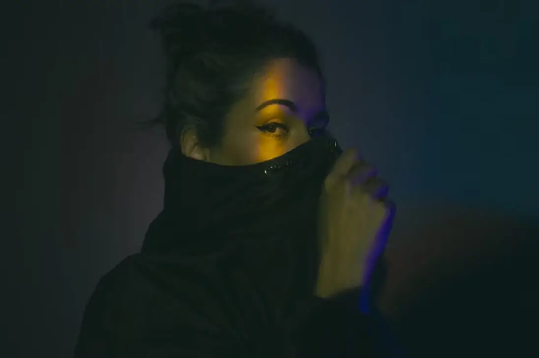 Woman with winged eyeliner peering over a black collar