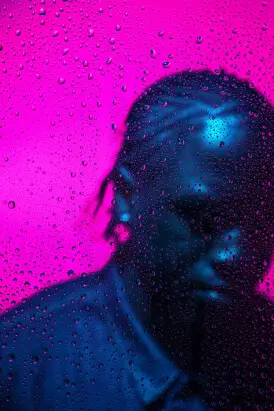 Silhouette behind a rain-covered window with a magenta background