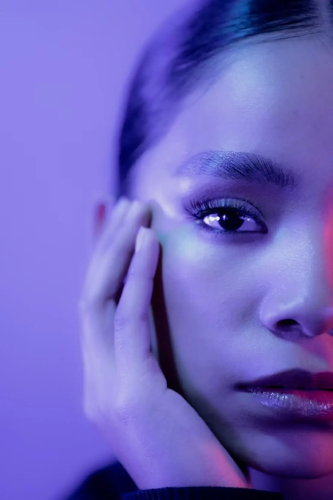 Close-up of a woman's face in purple and pink light