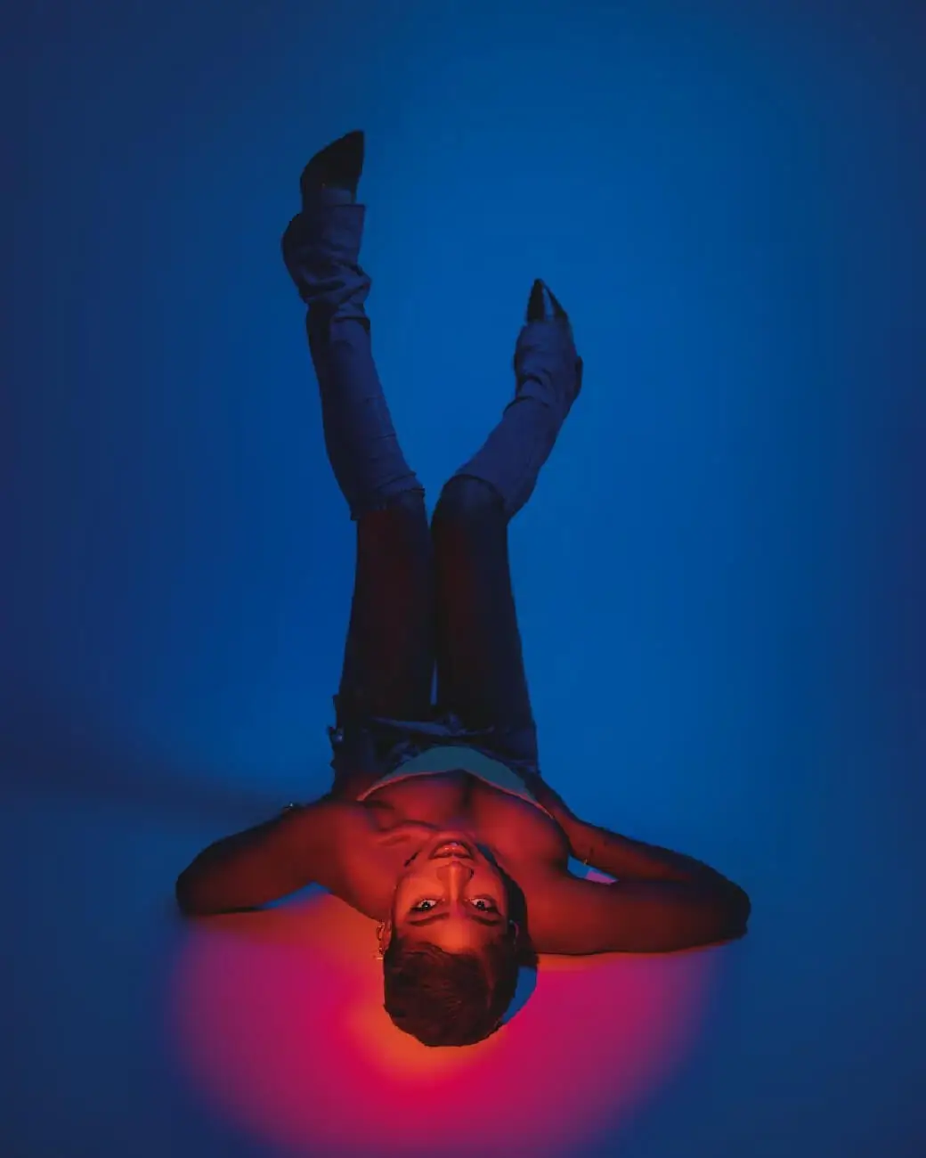 Person lying down with legs up, under blue and red light